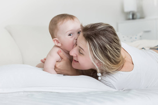 ベッドの上の母と男の子の幸せな笑みを浮かべて赤ちゃんの肖像画 - 写真・画像