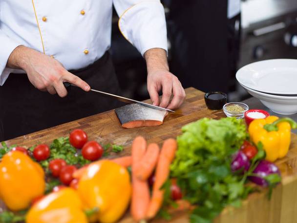 Руки шеф-повара готовят маринованное филе лосося для жарки на кухне ресторана - Фото, изображение