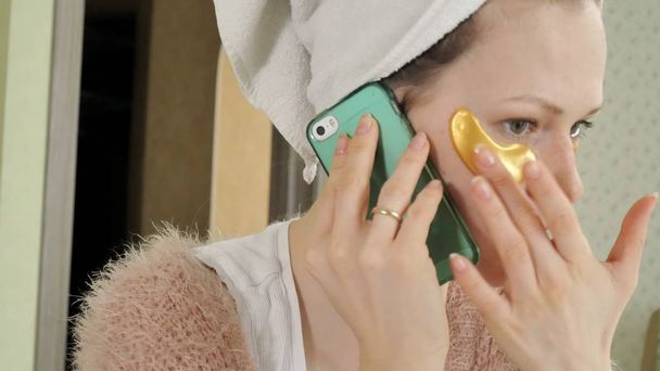 houkutteleva liike nainen soveltamalla kosmeettisia kasvojen täpliä kotona, puhelimessa puhuminen
 - Valokuva, kuva