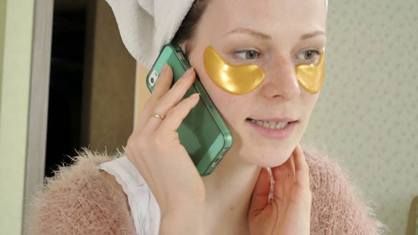atractiva mujer de negocios aplicando manchas faciales cosméticas en casa, hablando por teléfono
 - Foto, Imagen