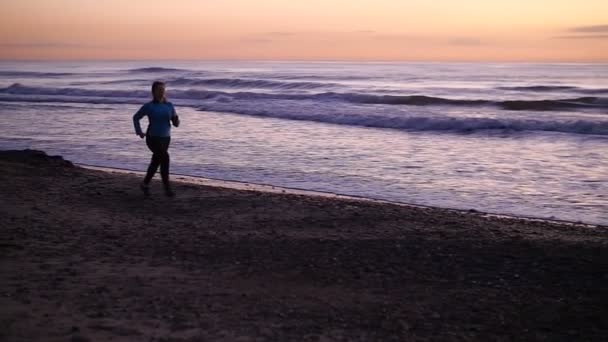 Młoda kobieta biegacza jogging na plaży - Materiał filmowy, wideo