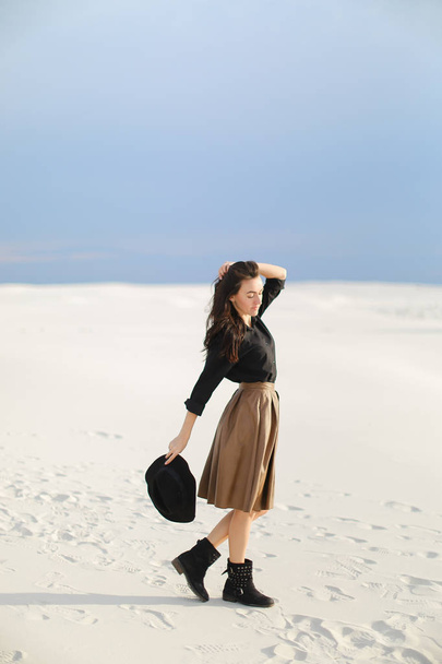 American stylish female photo model standing on snow and wearing skirt and black blouse. - Photo, Image