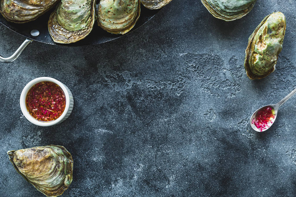 Top view of closed oysters with red sauce on grey background  - Photo, Image