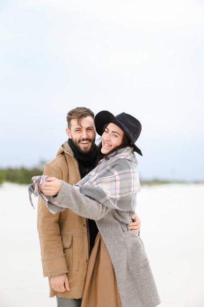 Happy smiling woman and man wearing coats and scarfs standing in winter snow background. - Photo, Image