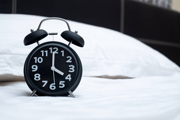 Reloj despertador vintage en la cama en el dormitorio en casa, despertar o idea de concepto de hora de la cama
. - Foto, Imagen