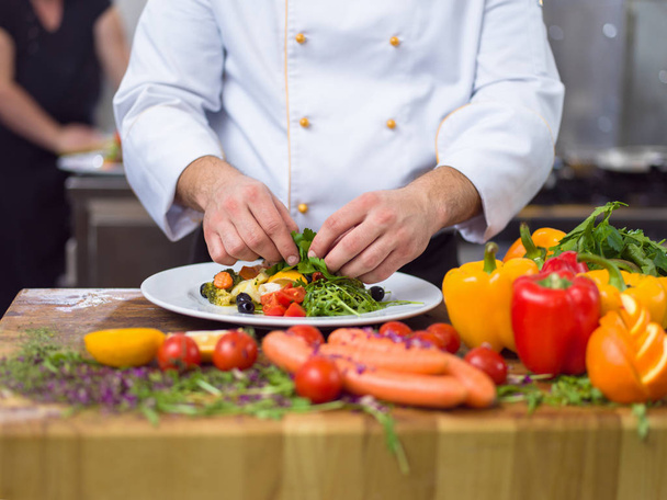 cook chef decorating garnishing prepared meal dish on the plate in restaurant commercial kitchen - Foto, Bild