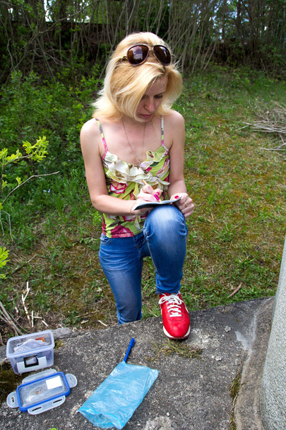 Mujer escribe en libro de registro de geocaching
 - Foto, imagen