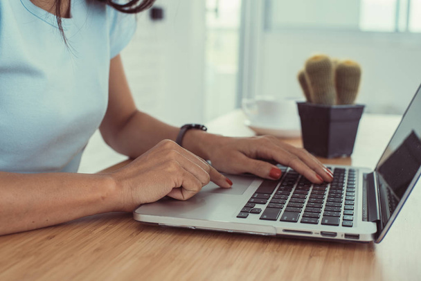 Kobieta w pracy w domu office dłoni na klawiaturze z bliska. Kobieta pisze na laptopie. Ręce kobiety na klawiaturze jej laptopa. Kobieta pracuje na laptopie w kawiarni. - Zdjęcie, obraz