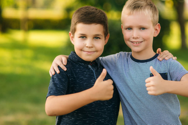 Δύο παιδιά παίζουν στο πάρκο. Δύο όμορφα αγόρια σε μπλουζάκια και Σορτσάκια να διασκεδάσουν χαμογελώντας - Φωτογραφία, εικόνα
