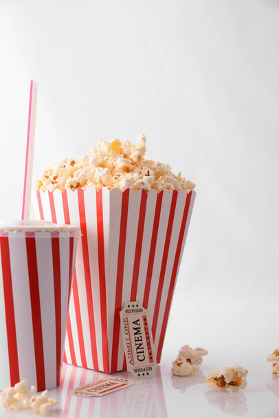Cinema moments concept with refreshment, popcorn and movie tickets on white background. Vertical composition. Front view. - Photo, image