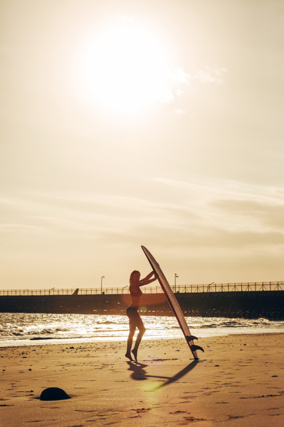 ženské surfař pózuje s surfu na pláži při západu slunce - Fotografie, Obrázek