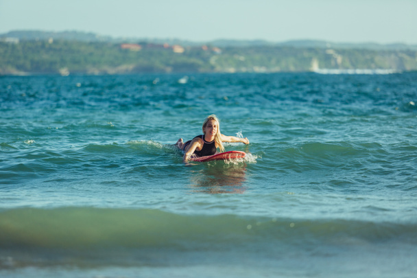beautiful sportswoman swimming on surfboard in water - Photo, Image