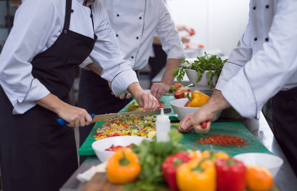 Professional team cooks and chefs preparing meals at busy hotel or restaurant  kitchen - Foto, Bild
