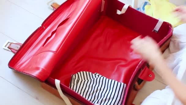 Vista recortada de las manos femeninas organizando la ropa en una bolsa de viaje
 - Imágenes, Vídeo