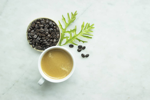 Top view, Closed up fresh mug coffee and green leave, beans in wooden tray on grey background, this menu made from dark roasted coffee - Foto, imagen