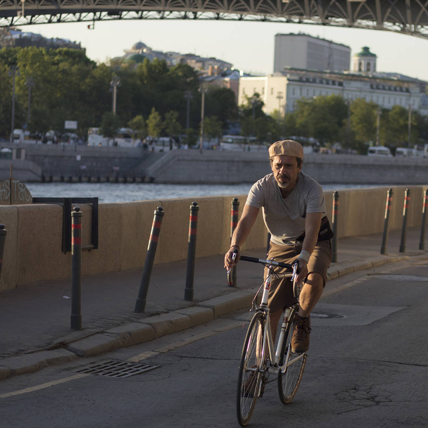 An elderly man is riding along the Moskva river embankment - Фото, изображение