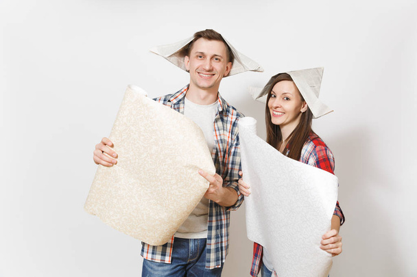 Young happy woman, man in casual clothes holding unrolled wallpaper rolls. Couple isolated on white background. Instruments, accessories, tools for renovation apartment room. Repair home concept - Valokuva, kuva