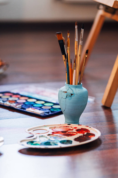 Artist paint brushes and palette on wooden background - Fotoğraf, Görsel