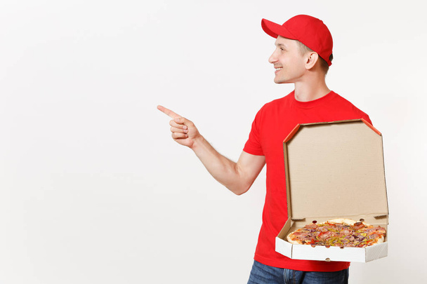Entrega hombre sonriente en uniforme rojo aislado sobre fondo blanco. Pizzaman masculino en gorra, camiseta que trabaja como mensajero o distribuidor sosteniendo pizza italiana en caja plana de cartón. Copiar espacio para publicidad
 - Foto, imagen