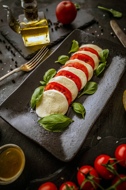 Delicious caprese salad with ripe tomatoes, mozzarella cheese and fresh basil leaves. Italian food. - Foto, Imagen