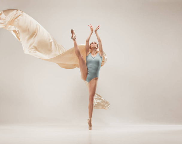 Moderne Balletttänzerin beim Ganzkörpertraining auf weißem Studiohintergrund. Ballerina oder Tänzerin mit Seidentanz auf weißem Studiohintergrund. Kaukasisches Modell auf Spitzenschuhen - Foto, Bild
