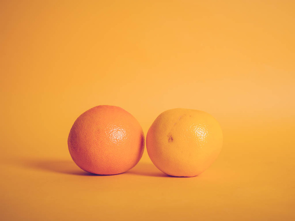 A red and yellow grapefruit on orange background - Foto, Imagem