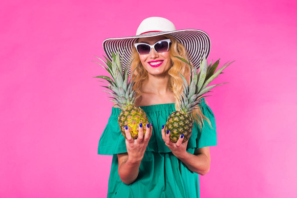 Happy young woman holding a pineapple on a pink background. Summer, diet and holidays concept - Fotó, kép
