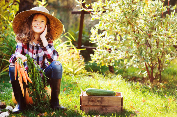happy farmer child girl sitting with autumn harvest in the garden. Growing fresh organic vegetables, natural healthy food and seasonal work concept. - Zdjęcie, obraz