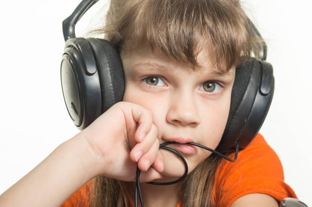 Πορτρέτο ενός κοριτσιού σε ακουστικά, σκεπτικός ματιά σε πλαίσιο - Φωτογραφία, εικόνα