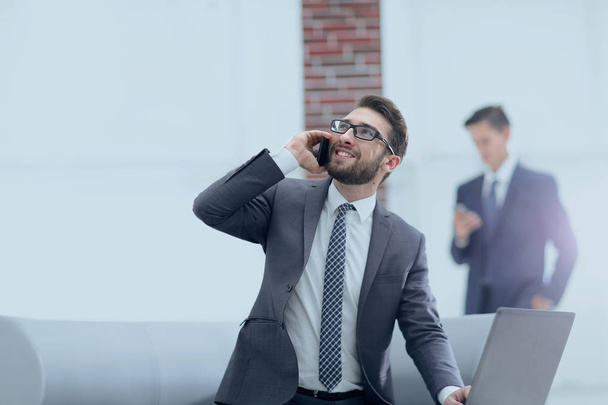Confident young man talking on phone in office - Photo, Image