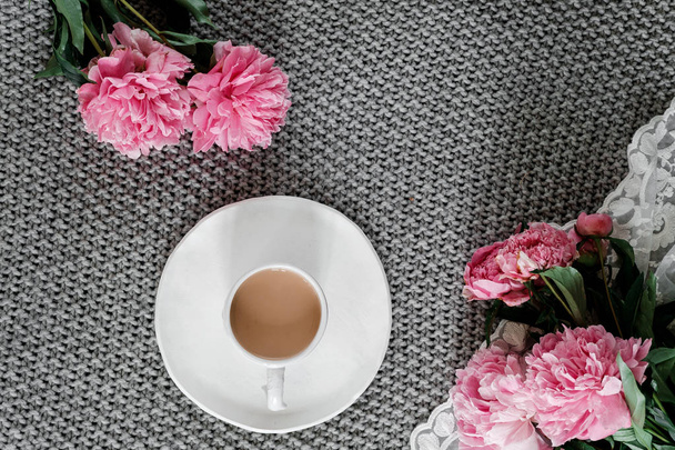A cup of coffee and peonies on a gray background - Фото, изображение