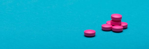 Bright pink pills on dark blue coloured background. Medication and prescription pills web banner with copy space. - Foto, Imagem