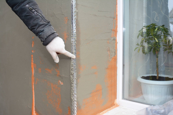 Ściana budynku wykonawca tynku, sztukaterie po sztywna izolacja w obszar problemu parapetu okna. - Zdjęcie, obraz