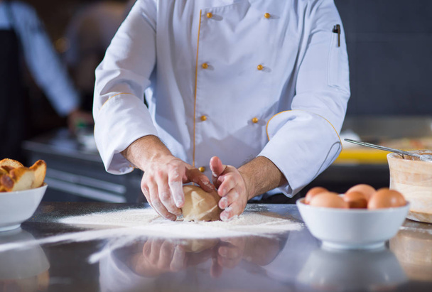 chef hands preparing dough for pizza on table sprinkled with flour closeup - Fotó, kép