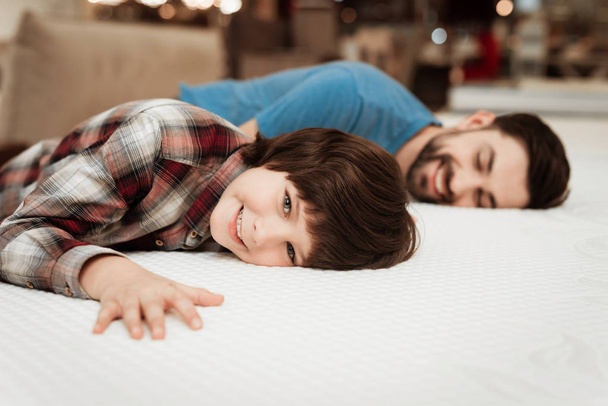 bearded father with young son testing mattress for softness in store - Photo, Image