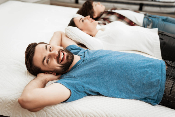 Parents and son relaxing on mattress in store and checking softness of mattress - Photo, Image