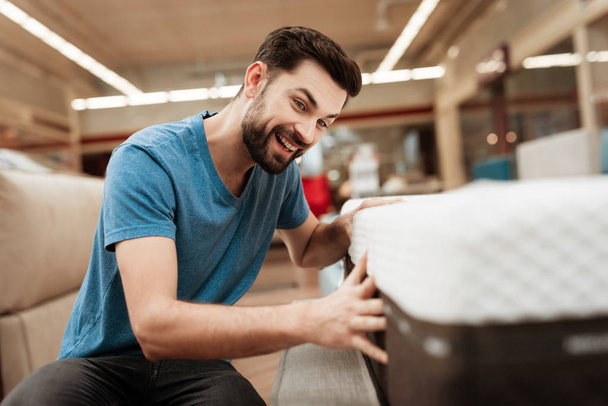 Young bearded man testing mattress in furniture store - Foto, Imagen