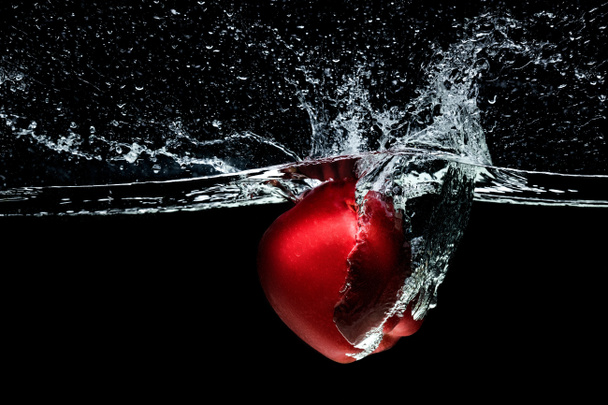 close up view of red apple falling into water isolated on black - Photo, Image