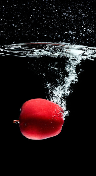 close up view of red apple falling into water isolated on black - Photo, Image