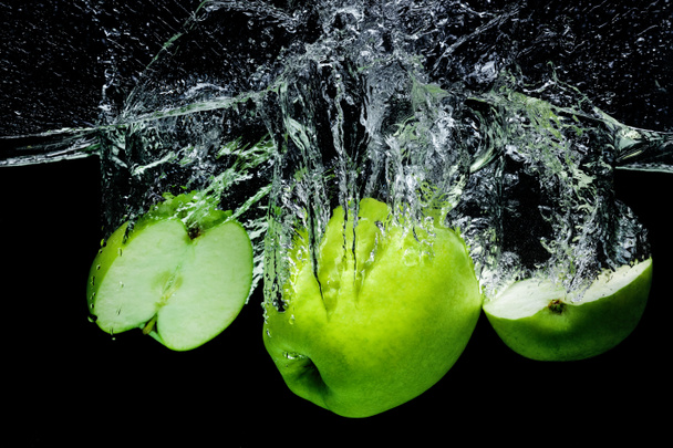 vista de cerca de manzanas verdes frescas en agua aislada en negro
 - Foto, Imagen