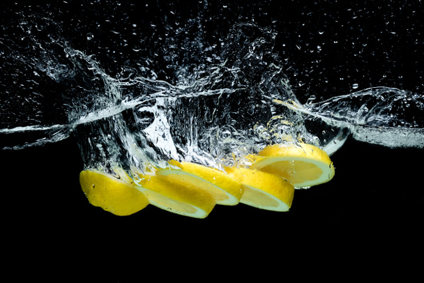 vue rapprochée des morceaux de citron frais dans l'eau avec éclaboussures isolées sur noir
 - Photo, image