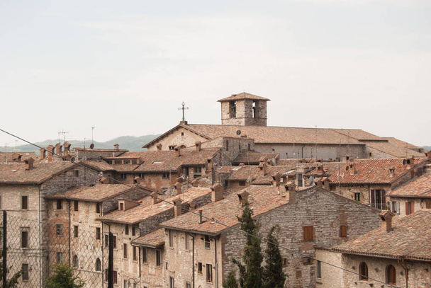 Onderdeel van de middeleeuwse stad met storical stenen constructies en kleine kerk vanaf de bovenkant van Gubbio - Foto, afbeelding
