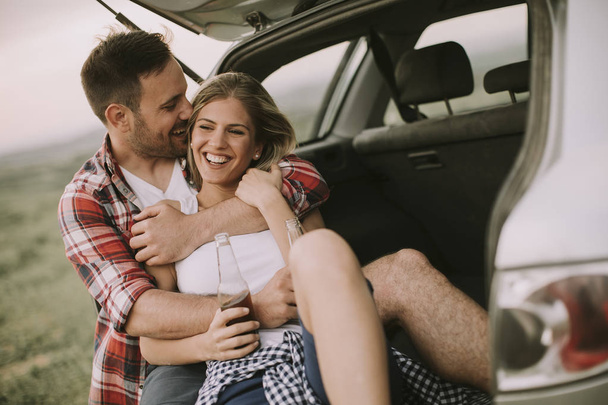 Amante casal sentado no carro trank durante a viagem na natureza
 - Foto, Imagem
