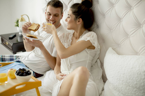 Jeune couple amoureux prenant le petit déjeuner au lit
 - Photo, image