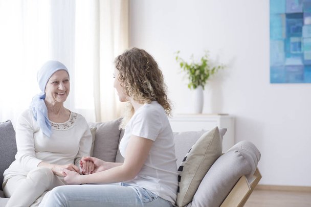 Smiling mother with cancer having fun with caring daughter at home - Foto, Imagen