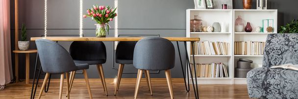 Four grey chairs standing by a hairpin table in dining room interior with reading corner - 写真・画像