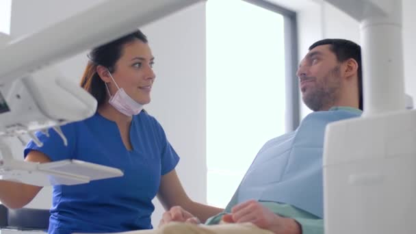 dentist and patient talking at dental clinic - Filmati, video