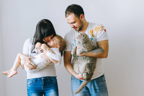 young family with son and cat on a white background after playing with paints - Photo, Image