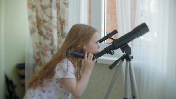 Küçük bir kız bir teleskopla evinin penceresinden görünüyor. - Video, Çekim