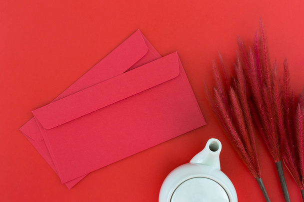 Felülnézet tartozékok tea pot és piros borítékot a kínai újév fesztivál díszek piros alapon - Fotó, kép